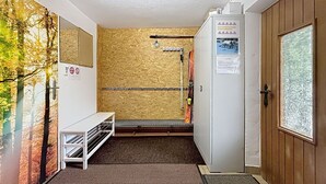 Quarto com suporte para esquis, um banco e uma porta com janela.