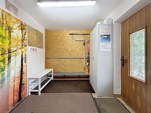 Ein Raum mit Skiständer, einer Bank und einer Tür mit Fenster.