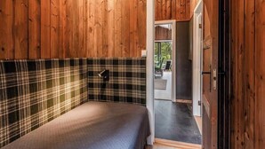 A bedroom with a plaid headboard, a bed with a quilt, and a door leading to a bathroom. - Cozy mountain cabin at 962m (Ål)
