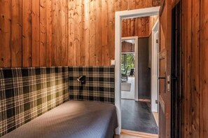 A bedroom with a plaid headboard, a bed with a quilt, and a door leading to a bathroom. - Cozy mountain cabin at 962m (Ål)