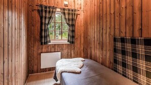 A room with wooden walls, a window with plaid curtains, a radiator, and a bed with a plaid blanket. - Cozy mountain cabin at 962m (Ål)