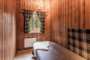 A room with wooden walls, a window with plaid curtains, a radiator, and a bed with a plaid blanket. - Cozy mountain cabin at 962m (Ål)