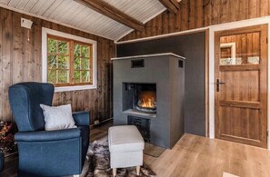 A cozy room with a fireplace, a blue armchair, and a wooden door. - Cozy mountain cabin at 962m (Ål)