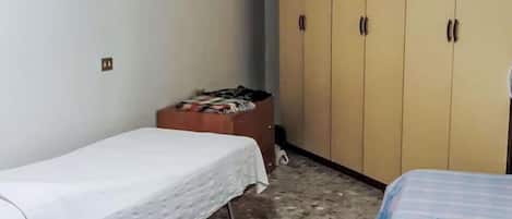 A room with two beds, a wardrobe, and a small table.