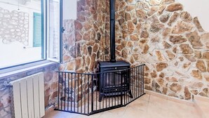 A stone wall with a black fireplace, a window with blue shutters, and a tiled floor. - Nice apartment for 6 guests with A/C and TV (Caramanico Terme)