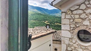A view from a window overlooking a mountainous landscape with terracotta roof tiles and stone walls. - Nice apartment for 6 guests with A/C and TV (Caramanico Terme)