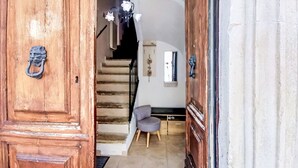 A wooden door with a metal handle, a staircase leading to a room with a gray chair, and a ceiling light fixture. - Nice apartment for 6 guests with A/C and TV (Caramanico Terme)