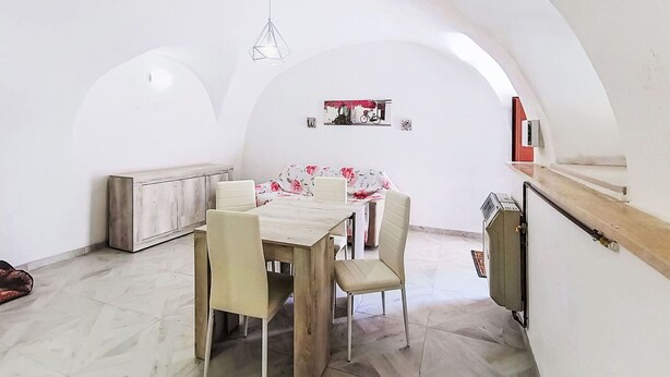 A dining area with a table and chairs, a bench, a hanging light fixture, and a wall-mounted shelf with a picture. - Nice apartment for 6 guests with A/C and TV (Caramanico Terme)