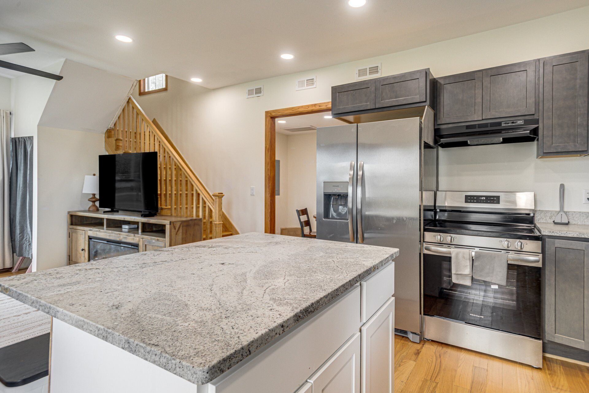 Una cocina moderna con encimeras de granito, electrodomésticos de acero inoxidable y una escalera de madera.