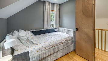 Une chambre à coucher avec un lit, une table de chevet, une fenêtre avec des rideaux et une porte en bois.