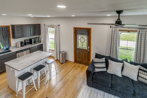 A compact living space with a kitchenette, a dining area, and a seating area with a sofa and cushions.