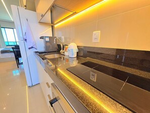Eine moderne Küche mit schwarzem Arbeitsplatz, Edelstahlgeräten und einem Fenster für natürliches Licht.