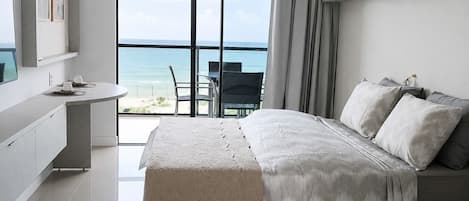 Un dormitorio moderno con una cama grande, un escritorio y vistas al océano.