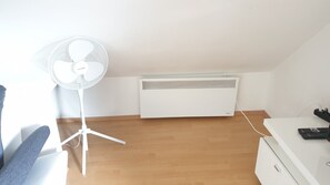 A room with a standing fan, a white heater, and a wooden floor. - Adorable 1-bedroom apartment in Brod 11 perfect for relaxing stays. (Brod 11)