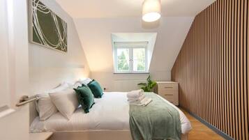 A bedroom with a bed, a window, a radiator, and a wall with vertical lines.