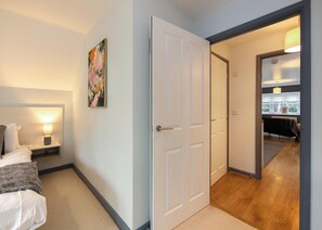 A hotel room with a bed, bedside lamp, and a door leading to a hallway. - 216a Bassett Green Apartments (Southampton)