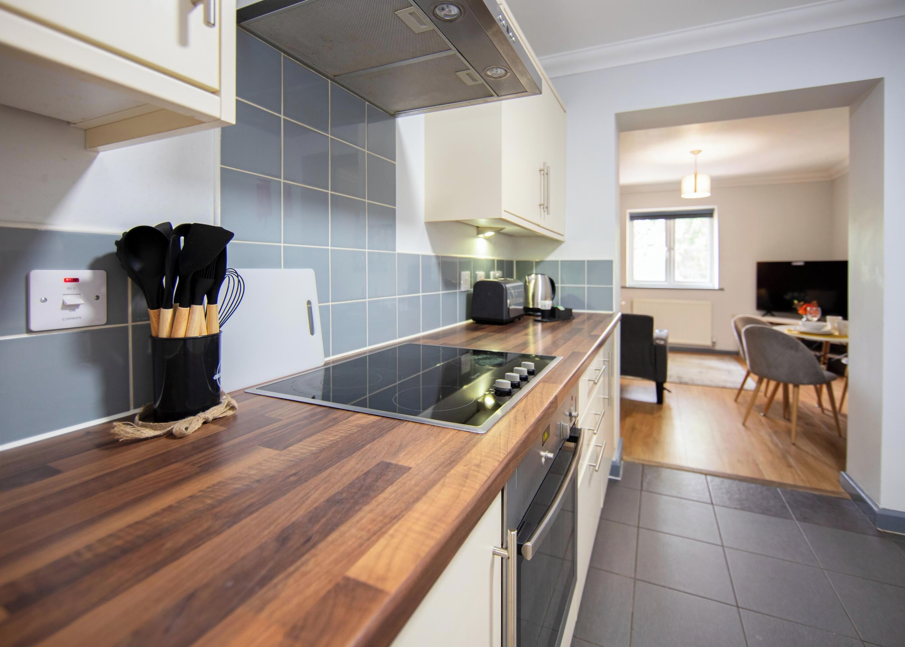 A modern kitchen with a wood countertop, built-in oven, and a dining area with a table and chairs.