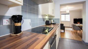 A modern kitchen with a wood countertop, built-in oven, and a dining area with a table and chairs.