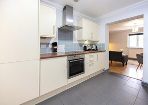 A modern kitchen with white cabinetry, a stainless steel range hood, and a built-in oven.
