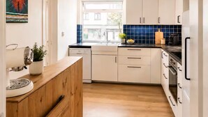 Una cocina moderna con armarios blancos, encimera de madera y salpicadero de azulejos azules.