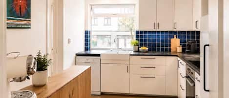 A modern kitchen with white cabinets, a wooden countertop, and a blue-tiled backsplash.