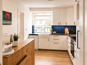 Eine moderne Küche mit weißen Schränken, einer Holzauskleidung und einer blau gefliesten Spritzschutzwand.