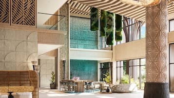 Un vestíbulo espacioso con techo alto, una zona de estar central y una escalera que conduce a plantas superiores.