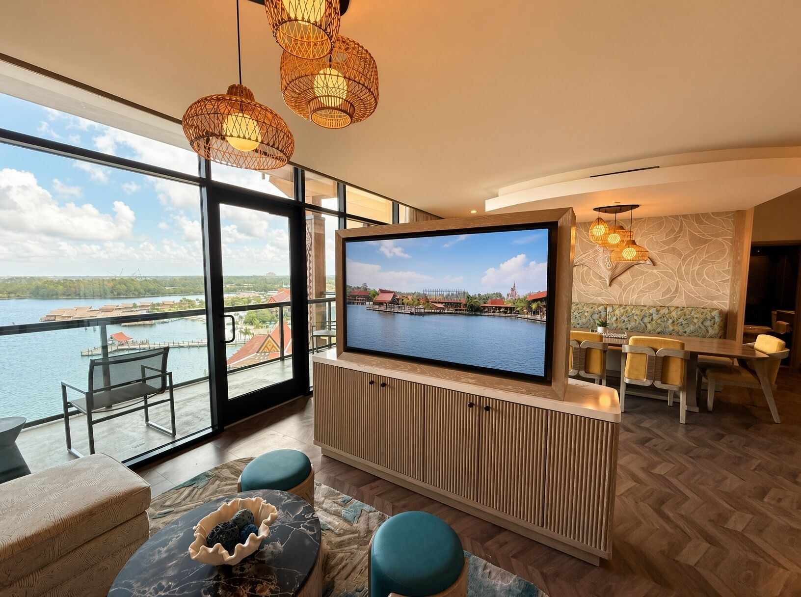A modern living room with a large TV, comfortable seating, and a view of a body of water.