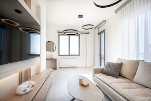 A modern living room with a sofa, a coffee table, a TV, and pendant lights. - Sofia`s Estates : Villa Savvas (Adults Only) (Lagoudi Zia)