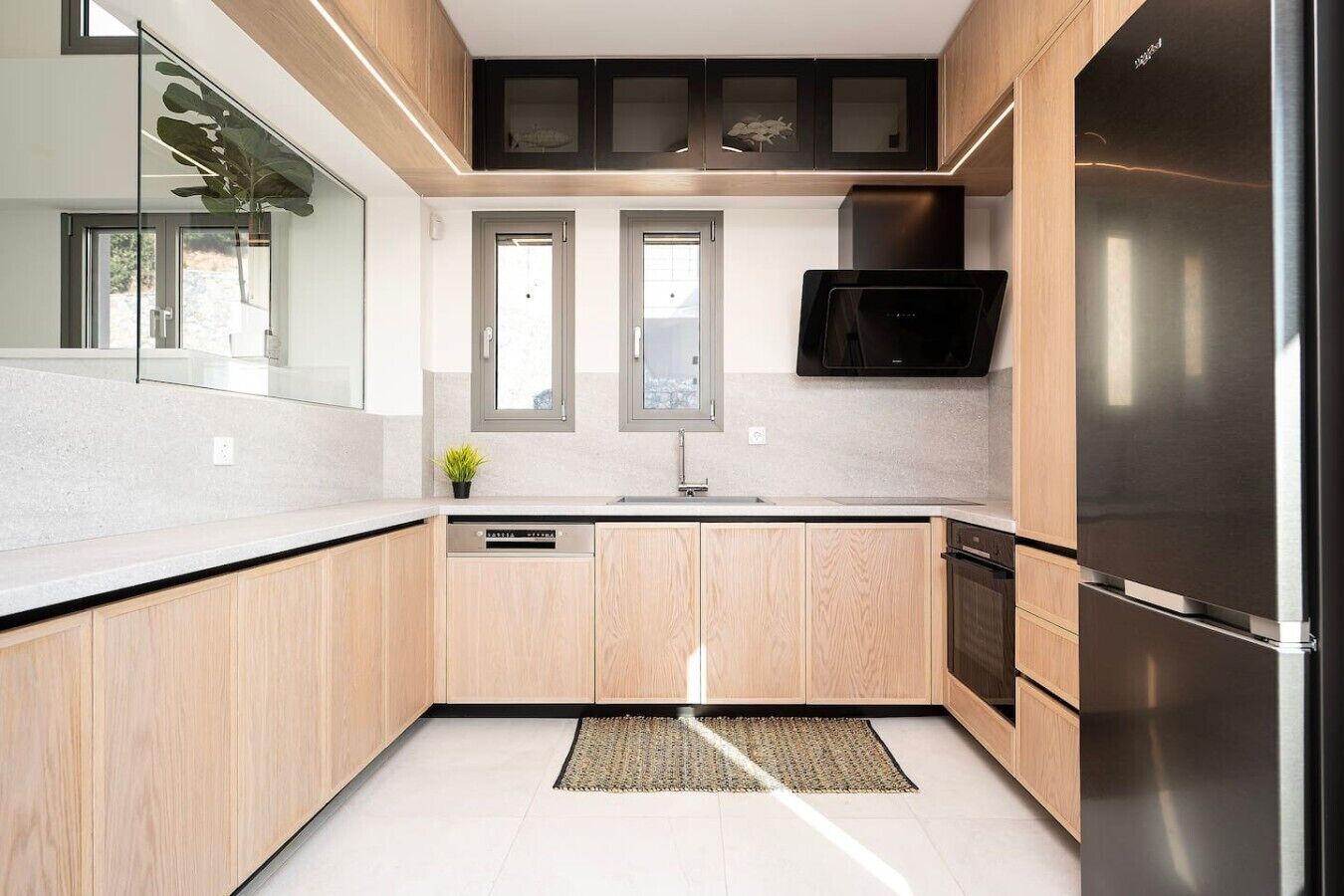 Una cucina moderna con mobili in legno, un frigorifero in acciaio inossidabile, una lavastoviglie e un forno a microonde.