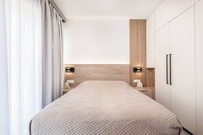 Ein modernes Schlafzimmer mit einem großen Bett, Nachttischen und einem Kleiderschrank.