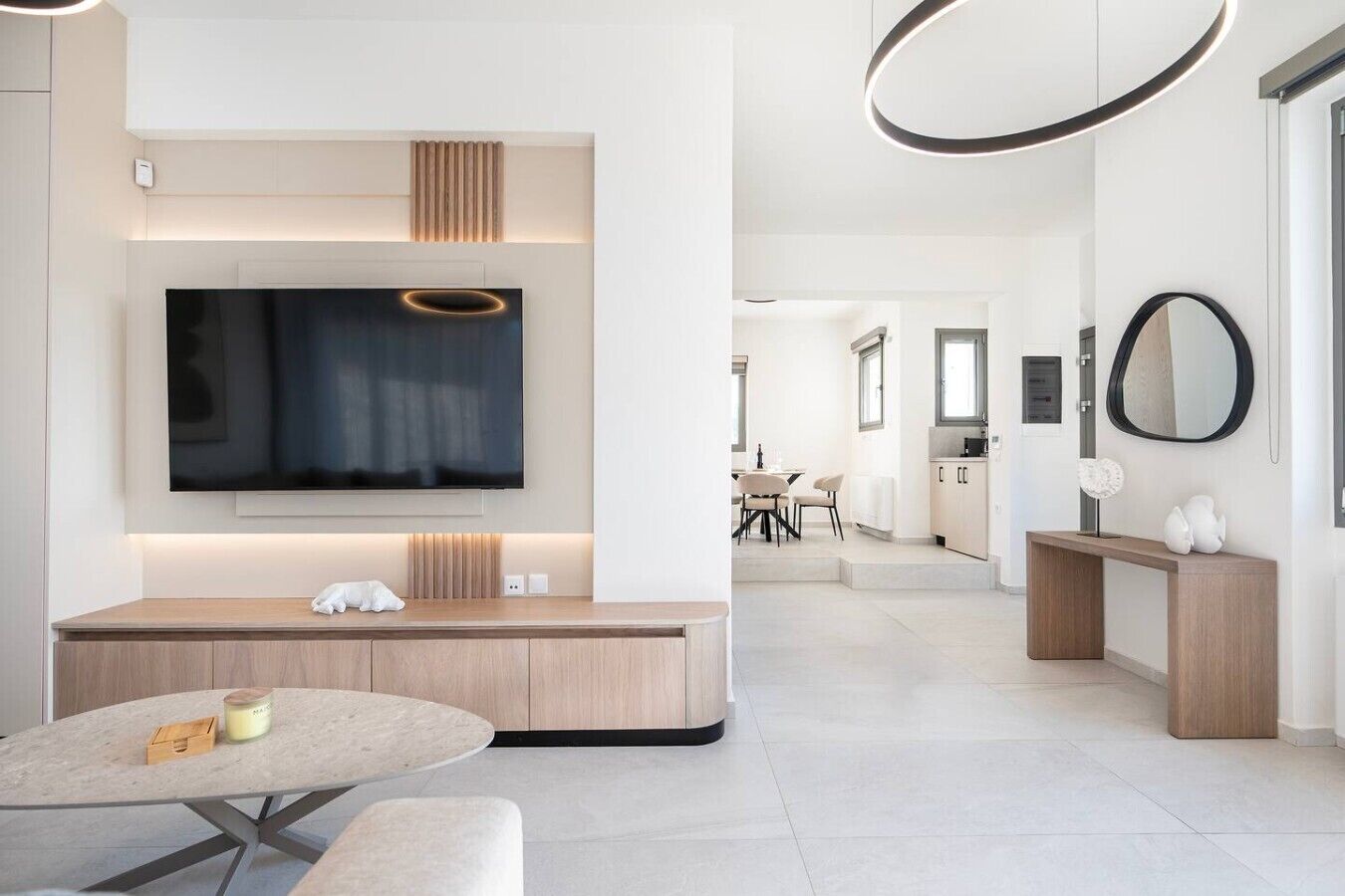 A modern living room with a flat-screen TV, a seating area, and a dining space.