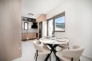 A modern kitchen with a dining area, large windows, and a view of the outdoors. - Sofia`s Estates : Villa Savvas (Adults Only) (Lagoudi Zia)