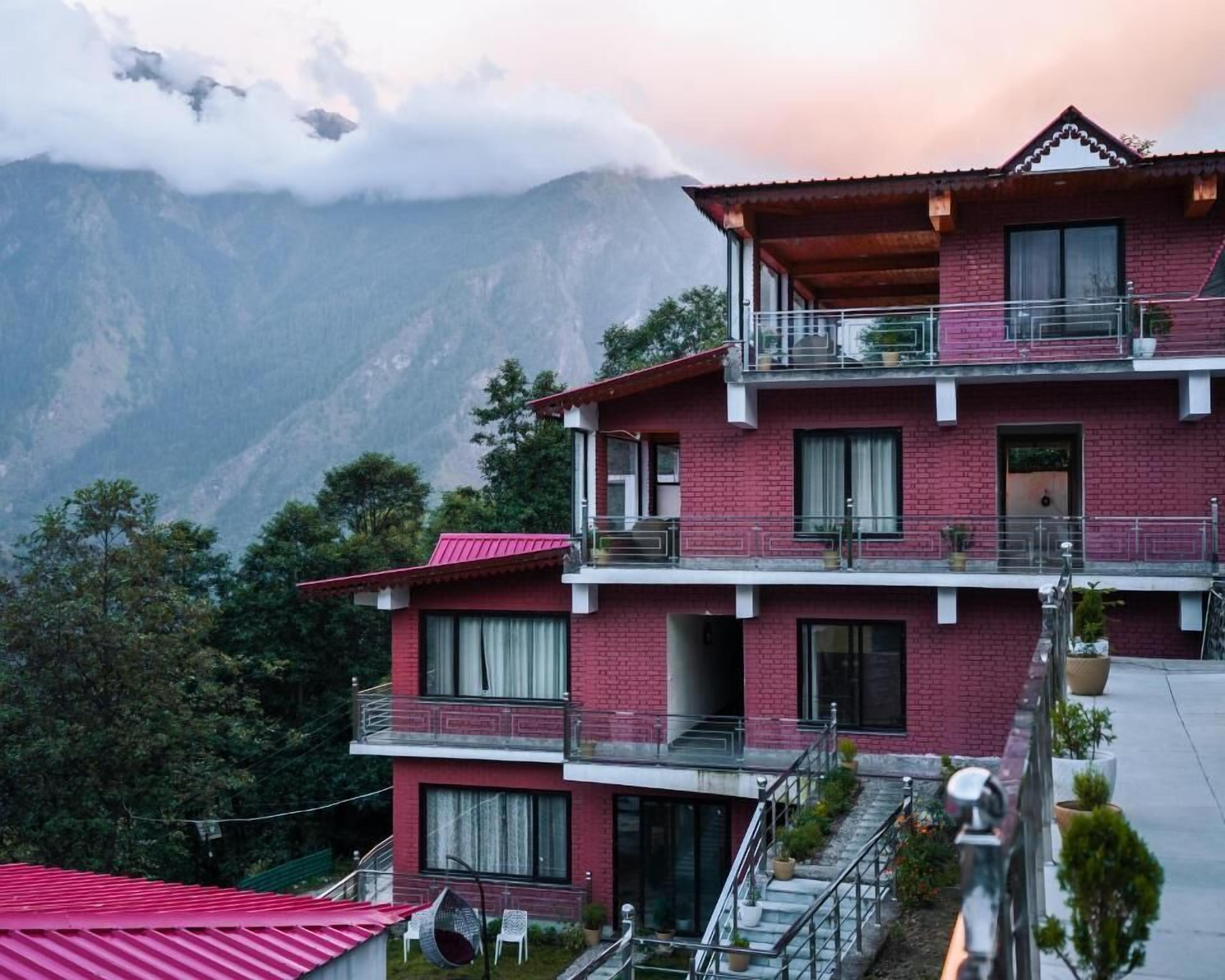 A multi-story building with balconies, a staircase, and a view of mountains.