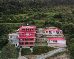 A multi-story building with a red roof, surrounded by lush greenery and terraced land.