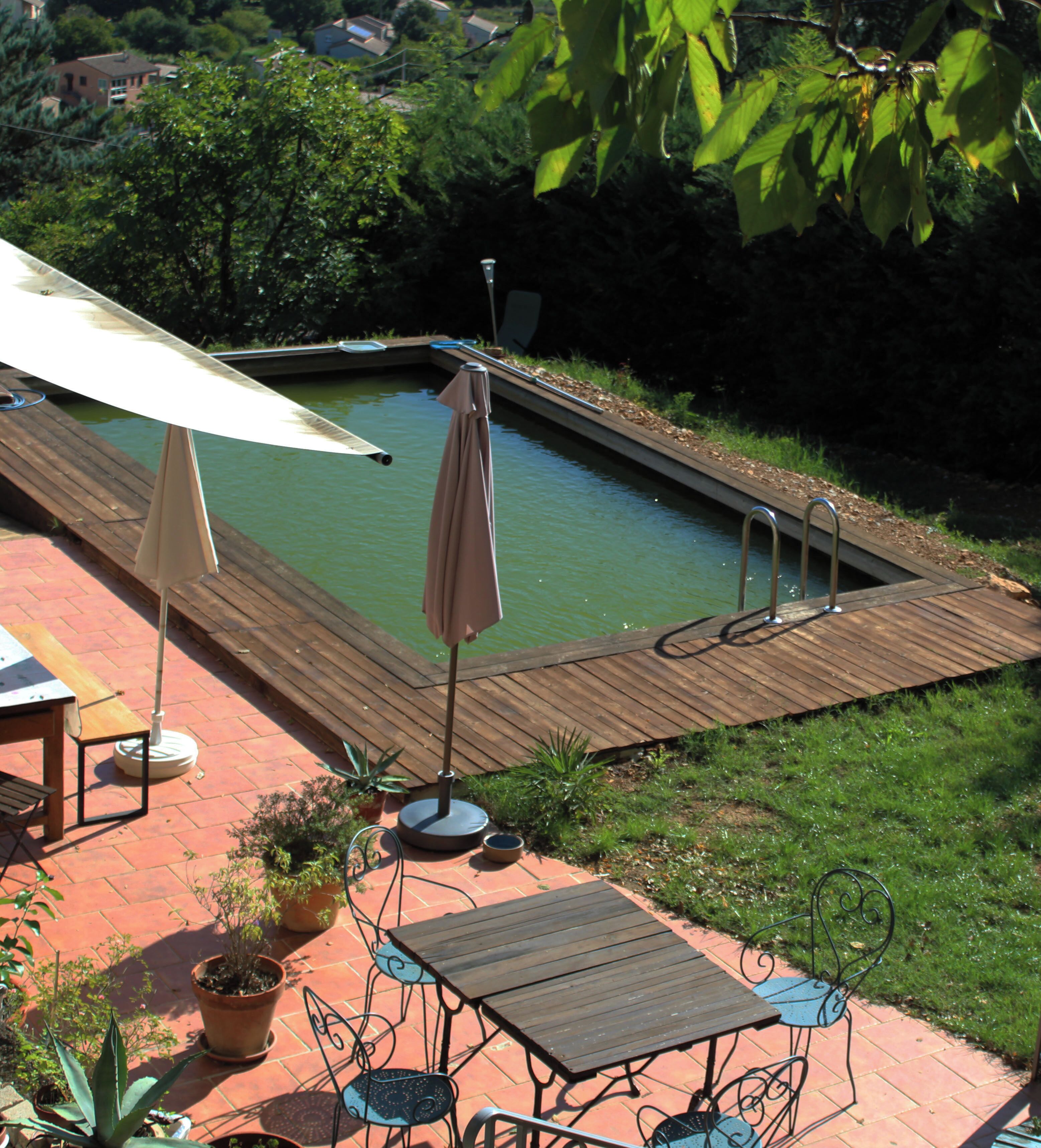 A wooden deck with a pool, outdoor furniture, and potted plants.