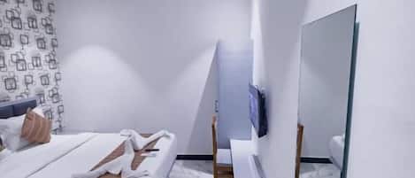 A modern bedroom with a bed, a TV, a mirror, and a ceiling fan.