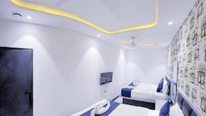 Habitación de hotel con dos camas, un televisor de pantalla plana y una pared con un diseño geométrico.