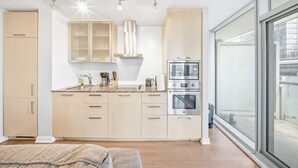 A modern kitchen with a built-in microwave, oven, and gas stove. There is a window providing a view of the outside. - Founder's Club York - 3 Bedroom Condo  (Toronto)