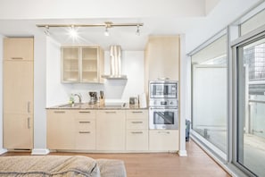 Eine moderne Küche mit integriertem Mikrowellenherd, Backofen und Gaskochfeld. Ein Fenster bietet Blick ins Freie.