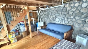 Ein Holzinnenraum mit einer Steinwand, einem blauen Sofa, einer Bank und einer Treppe.