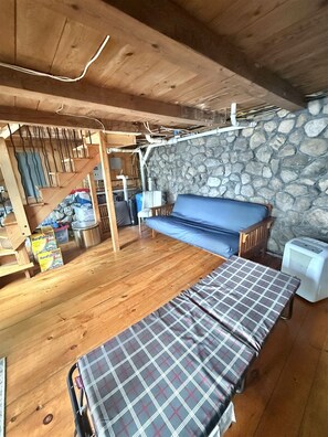 Ein Holzinnenraum mit einer Steinwand, einem blauen Sofa, einer Bank und einer Treppe.