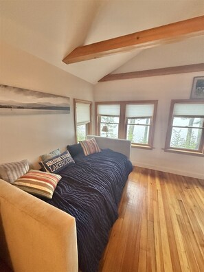 A bedroom with a bed, a window, and a wooden ceiling. - WATERFRONT ON THOMAS POND (Casco)
