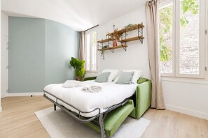 A modern bedroom with a bed, green sofa, and a plant. - Lavie Maison: Elegant Studio near Montmartre (Paris)