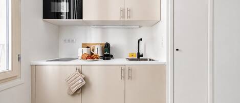 A kitchen with a microwave, toaster, kettle, and sink.