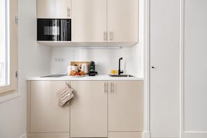 A kitchen with a microwave, toaster, kettle, and sink.