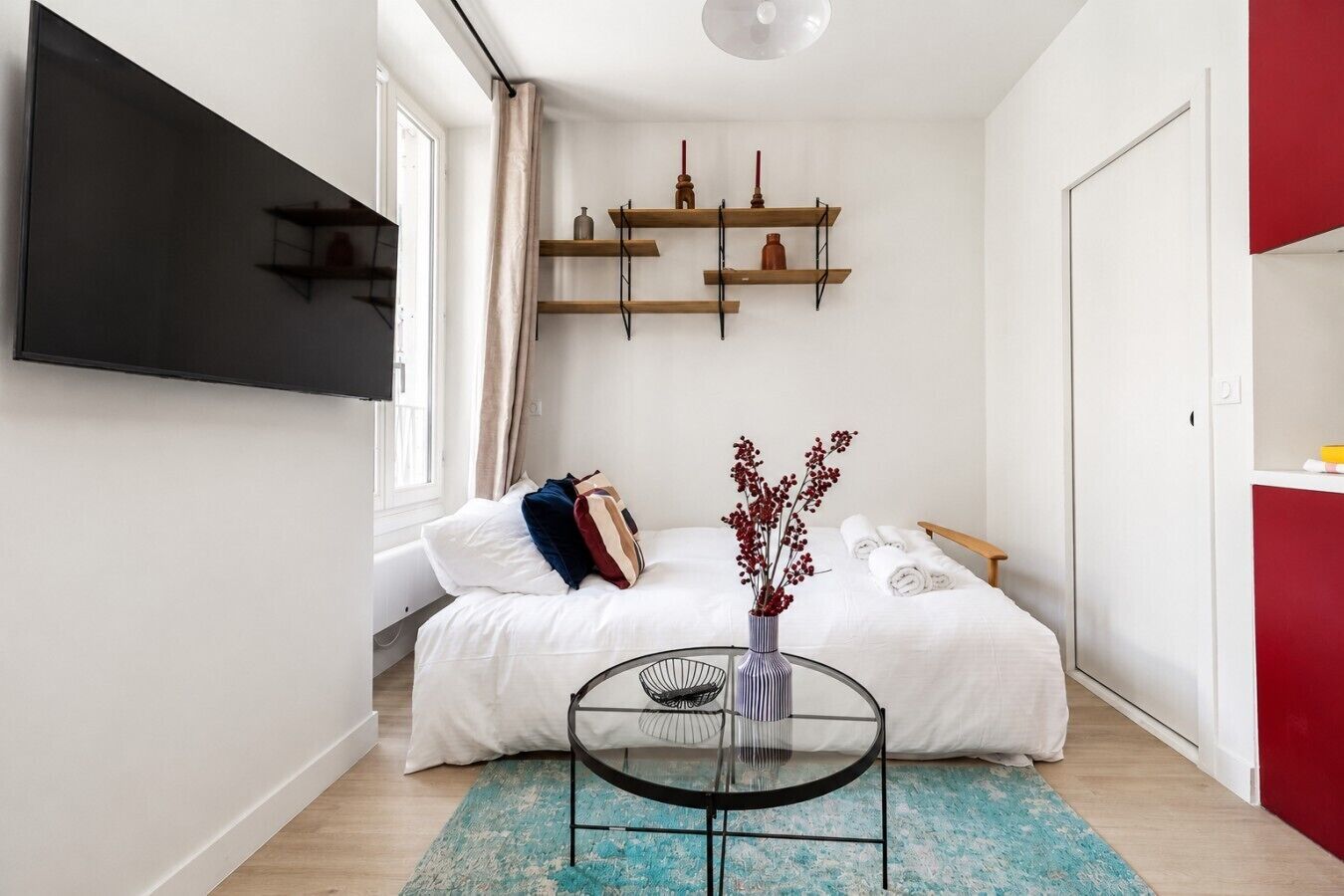 A bedroom with a bed, bedside table, and a wall-mounted TV.
