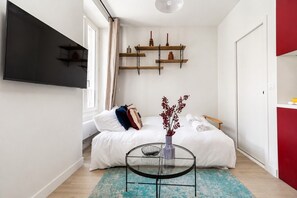 A bedroom with a bed, bedside table, and a wall-mounted TV. - Lavie Maison: Welcoming Apartment in Montmartre (Paris)