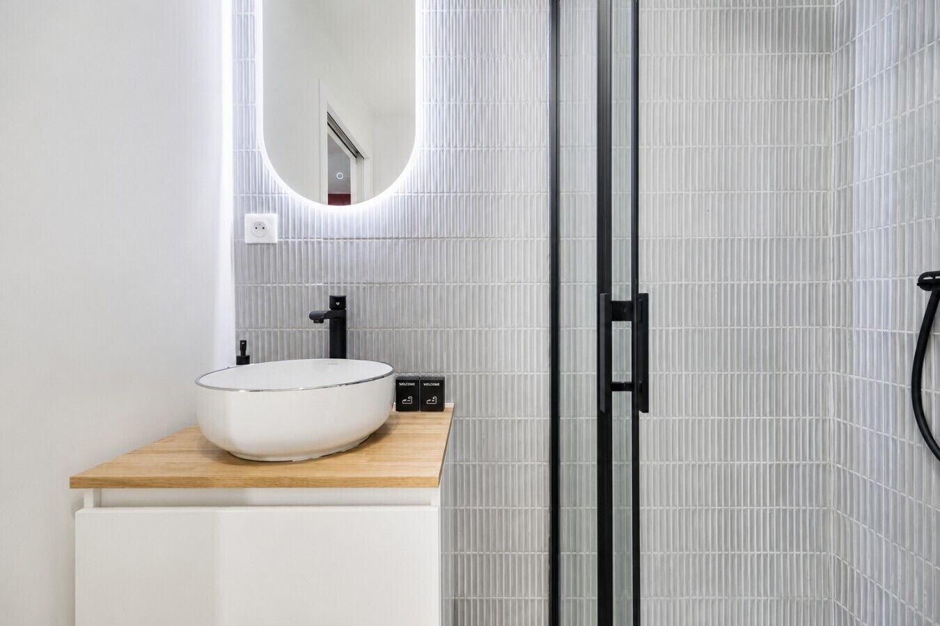 A modern bathroom with a round white sink, black faucet, and a wooden countertop.