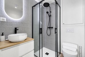 Ein modernes Badezimmer mit einer gläsernen Duschkabine, einem weißen Waschbecken und einer Toilette.